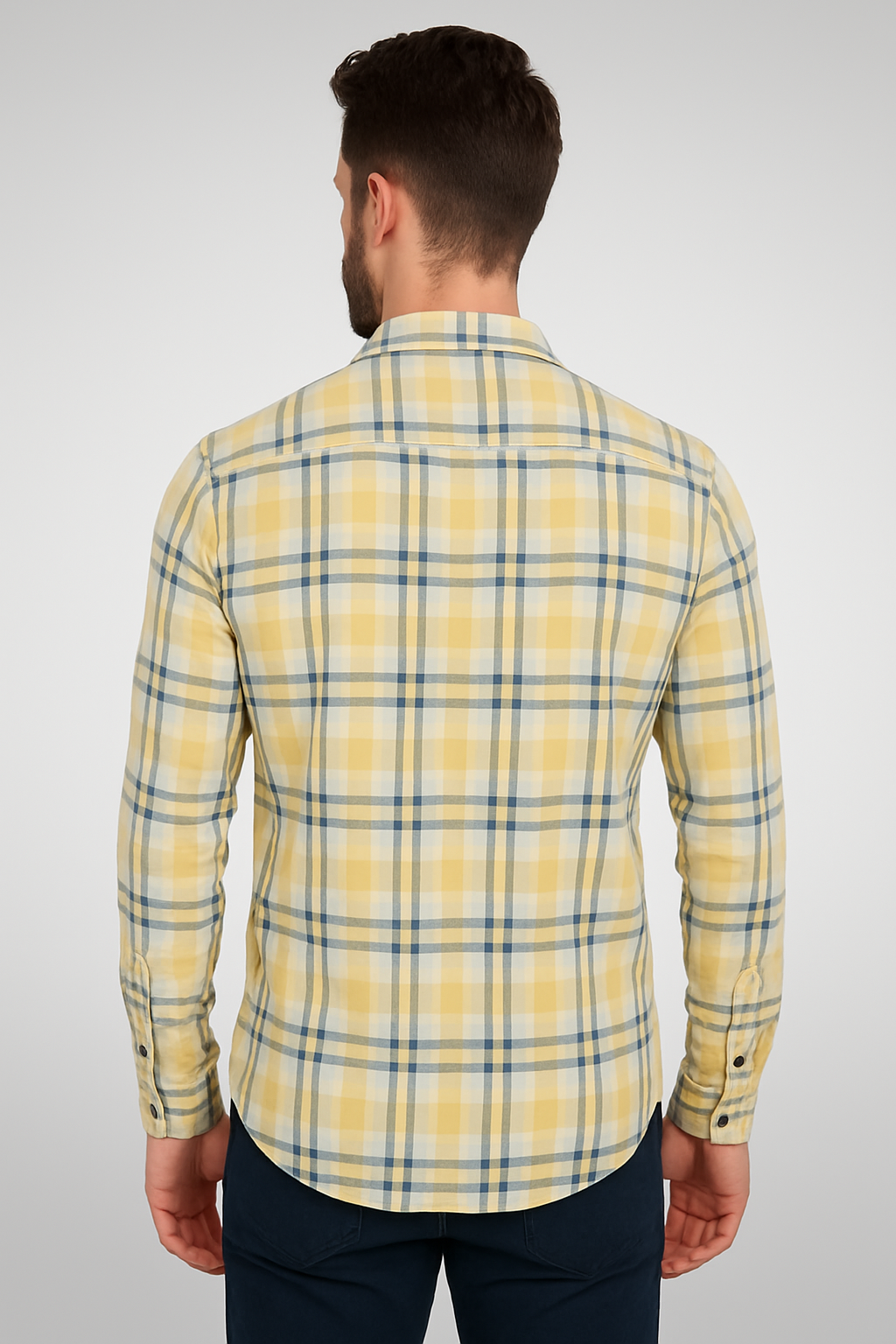 Man wearing a yellow plaid shirt on a plain background