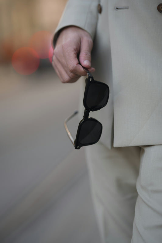 A man in a suit holding a pair of sunglasses