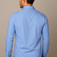 Man wearing a light blue dress shirt against a beige background