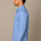 Man wearing a light blue dress shirt against a beige background