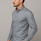 Man wearing a light gray button-up shirt against a gray background