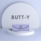 Purple pouch with 'BUTT-Y' branding on a light gray background