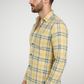 Man wearing a yellow plaid shirt against a gray background