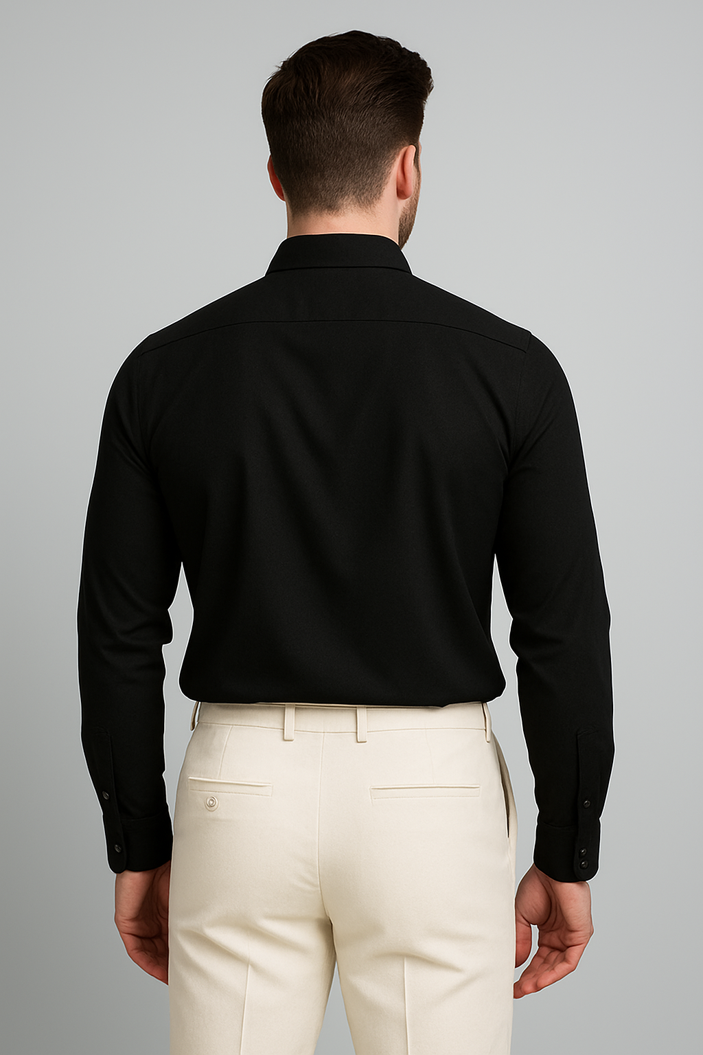 Man wearing a black shirt and beige pants against a gray background