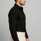 Man wearing a black dress shirt and beige pants against a gray background