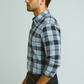Man wearing a blue and black plaid shirt against a light gray background
