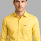 Man wearing a yellow shirt with a logo on a gray background