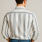 Man wearing a striped shirt and jeans against a plain background