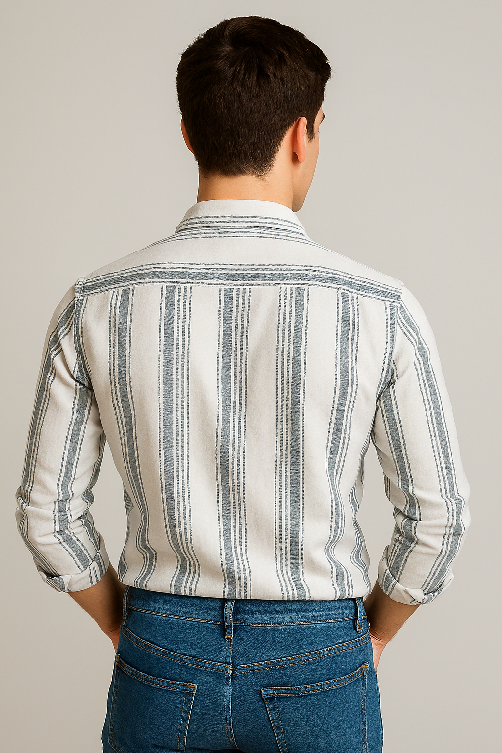 Man wearing a striped shirt and jeans against a plain background