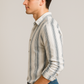 Man wearing a striped shirt and blue jeans against a plain background