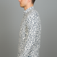 Man wearing a patterned shirt and jeans against a gray background