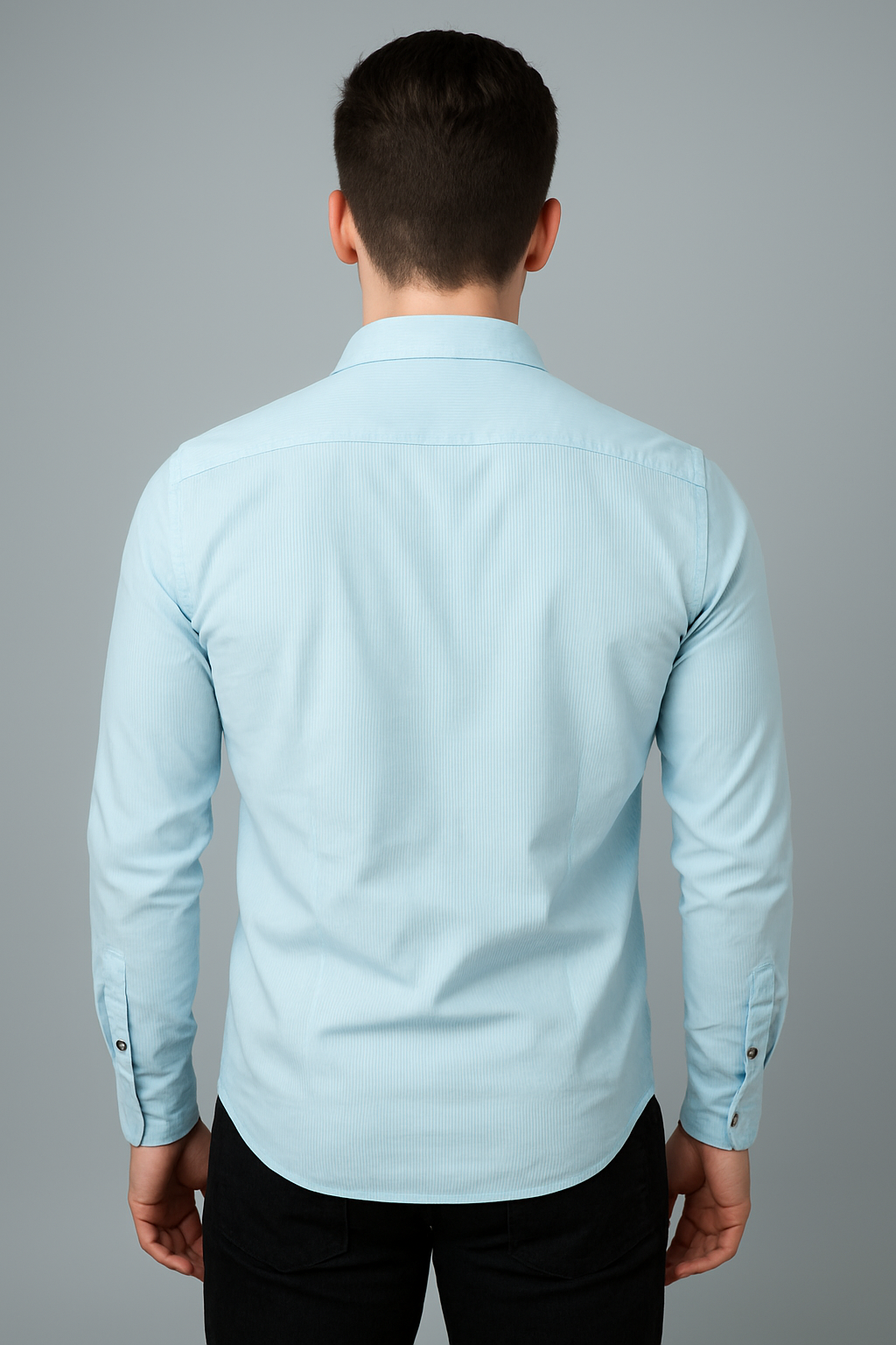 Man wearing a light blue dress shirt against a gray background
