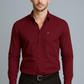 Man wearing a burgundy dress shirt and black pants on a gray background