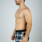 Man wearing plaid swim shorts on a gray background